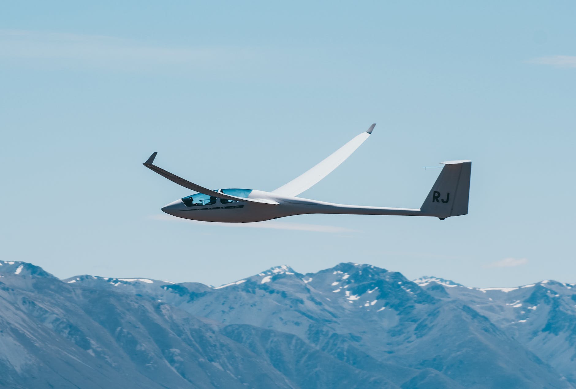 a sail plane flying over the mountains